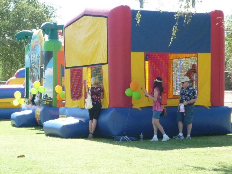 family and kids playing at park on bounce house